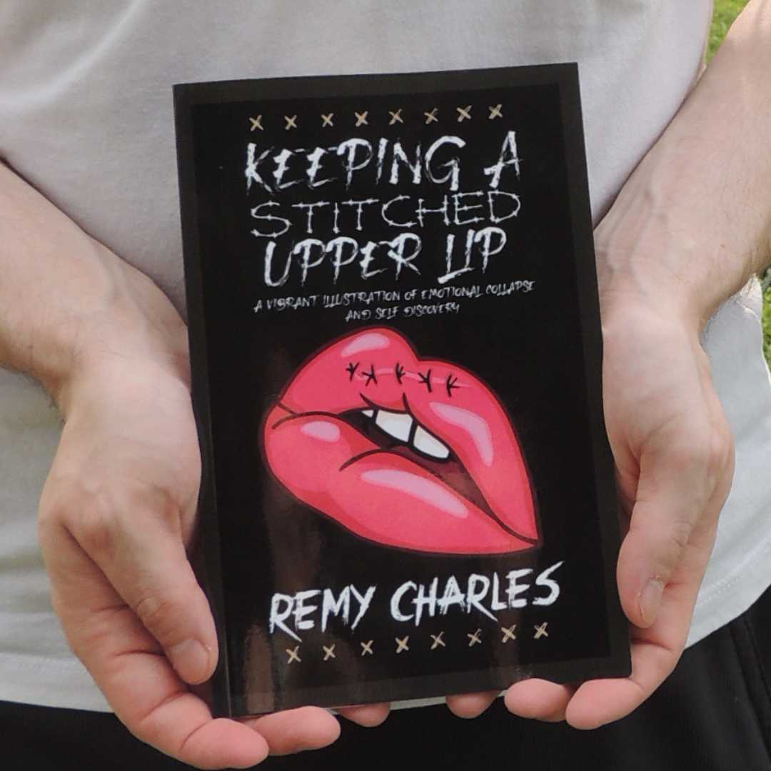 A pair of hands holding a paperback copy of Keeping A Stitched Upper Lip written by Remy Charles